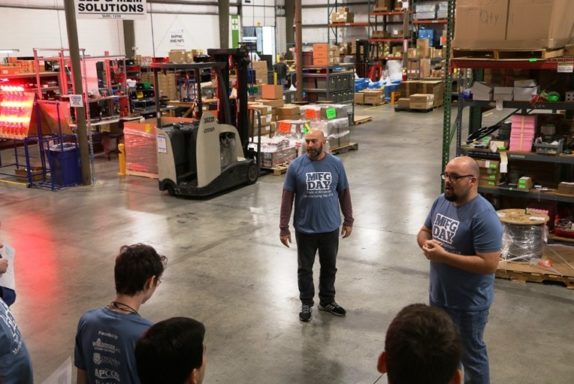 Le directeur des opérations, Marc, et le superviseur de la production, Jacob, présentent les étudiants à l'entrepôt de production le jour de la fabrication.