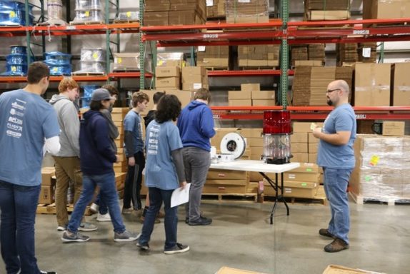 El supervisor de producción, Jacob, explica el proceso de fabricación de luces de obstrucción de xenón y LED a los estudiantes en el Día de la fabricación 2018