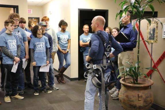 Field Services supervisor, Levi, dons his tower climber safety harness and explains tower safety to students at Manufacturing Day.