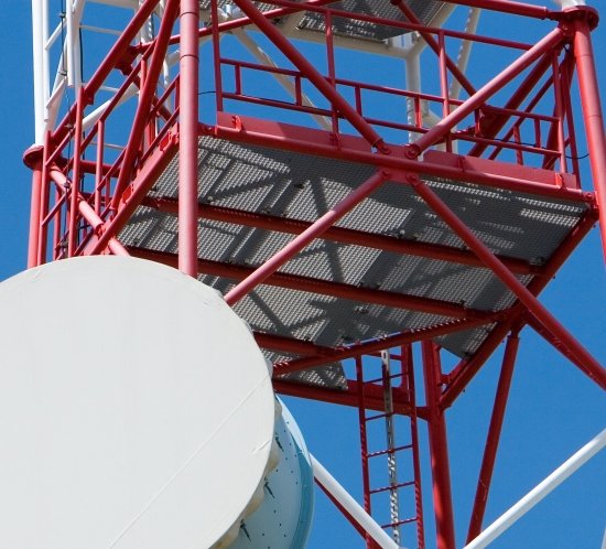 A white and red painted tower with microwave antenna