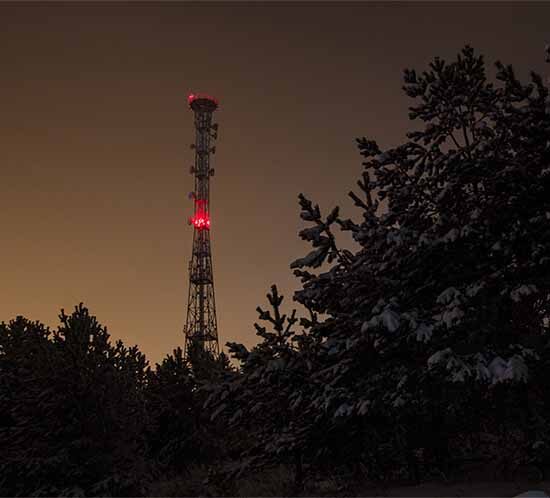 Communications structure with red tower light at night