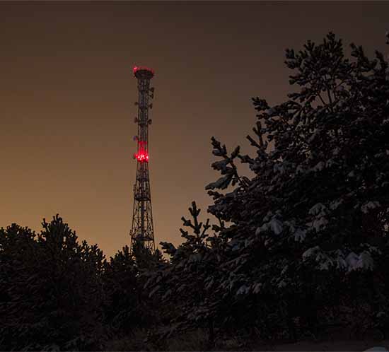 Communications structure with red tower light at night